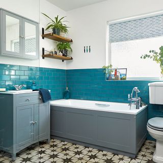 Bathroom with grey bath panels and sink cabinetry alongside turquoise metro wall tiles