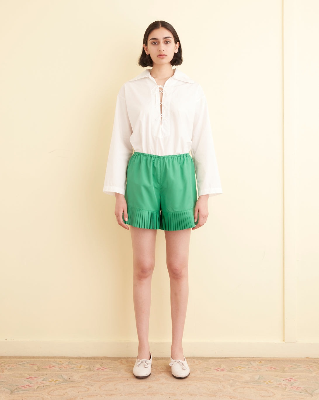 Model wearing Bode pleated shorts.