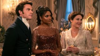 (L to R) Jonathan Bailey as Anthony Bridgerton, Simone Ashley as Kate Sharma, Ruth Gemmell as Lady Violet Bridgerton standing together.