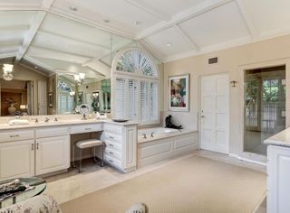 A large primary bathroom with a built-in bathtub, a large vanity and a rug