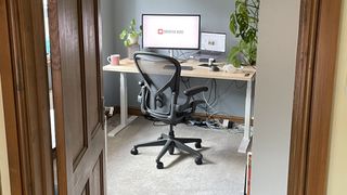 A photo through a doorframe, showing an office set up, including the Herman Miller Aeron chair. 