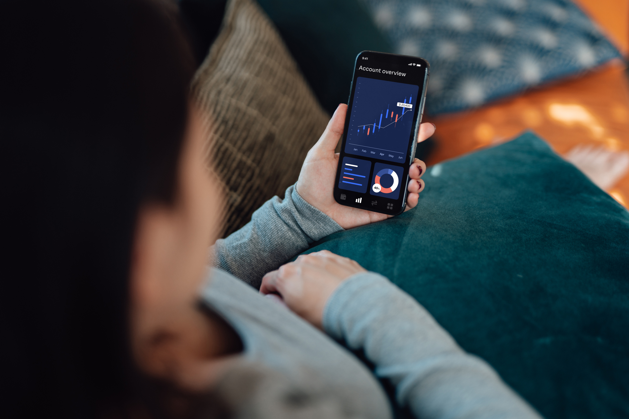 woman using mobile banking on smartphone while sitting on sofa at home investing in index funds