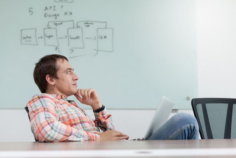 A man sits at a desk, daydreaming