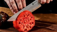 HexClad Damascus steel knife slicing a fresh tomato