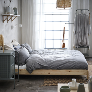 Ikea Utaker stackable bed made into double bed with gray bedspread, with large window and white linen curtains