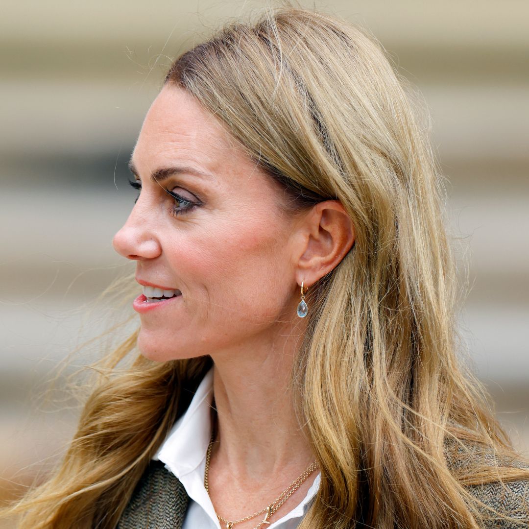 Kate Middleto smiling and turning her head to the side in front of a staircase