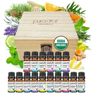 A wooden hinge lid box with an array of small amber glass essential oil bottles in front. 