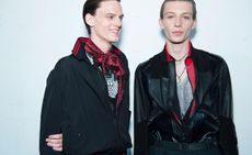 2 male models wearing black & red clothing, smiling at the camera