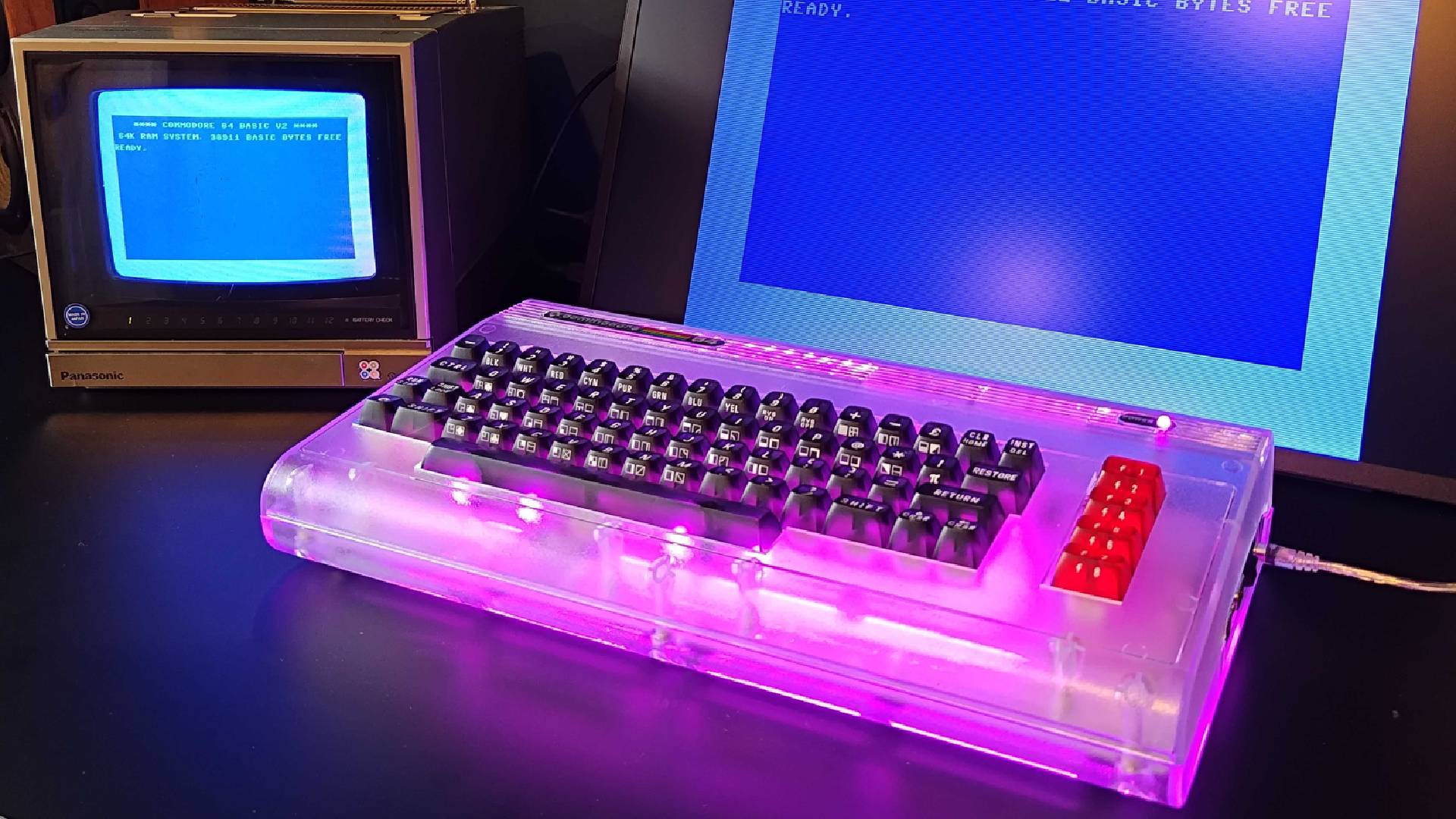 Commodore 64 Ultimate with purple RGB lighting next to CRT PVM and portable monitor with blue Basic screen displayed.