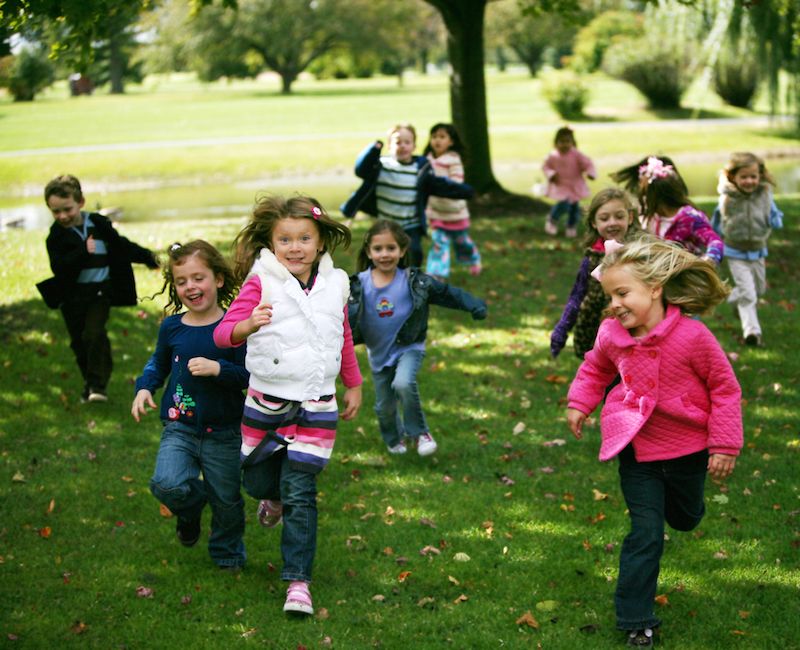 A group of children runs in a park.