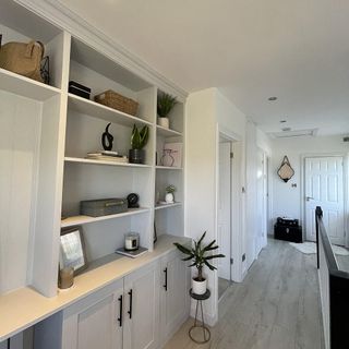 hallway with white wall wooden floor and white shelve