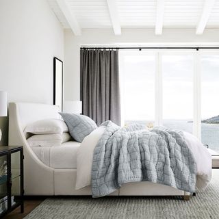 Side view of a Cloud Quilt on a bed against a white wall.