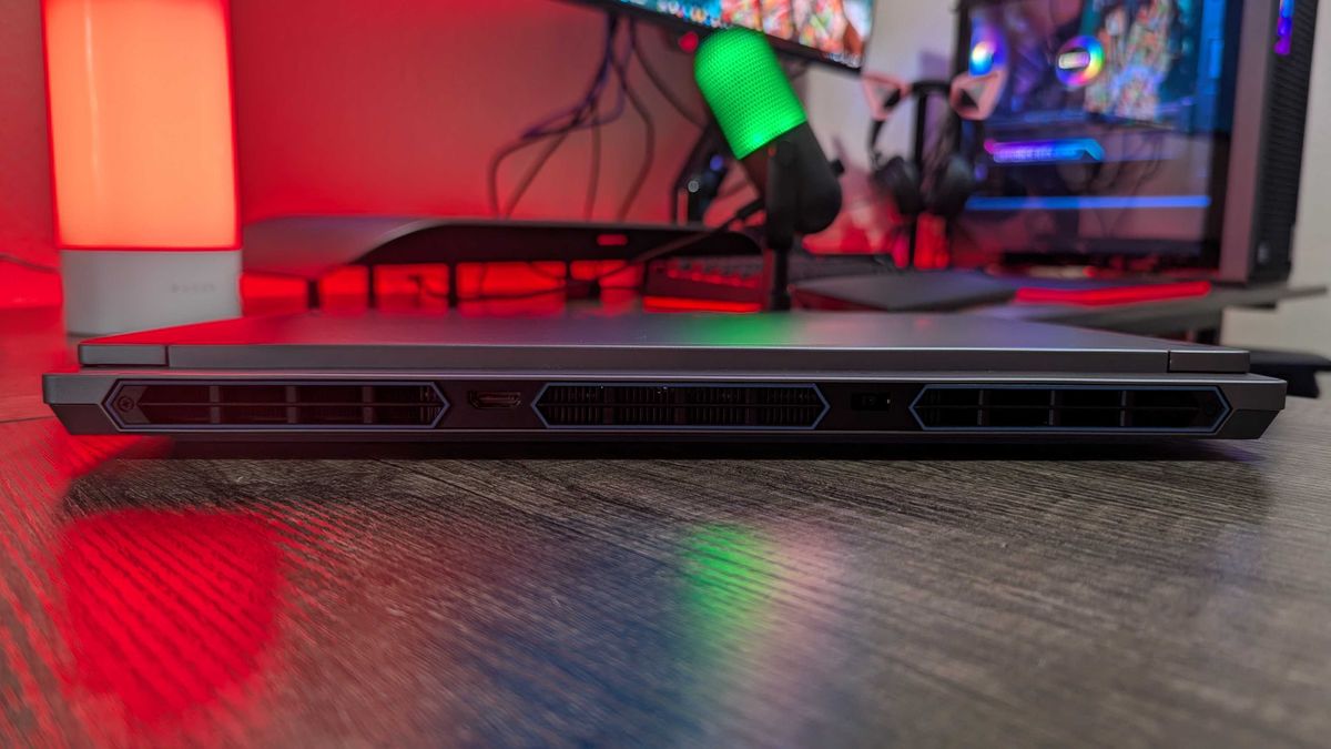 A Lenovo Legion 5i (Gen 9) gaming laptop on a desk with a red backlight, seen from the rear to show the HDMI 2.1 port and 230W DC power port.