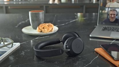 Jabra Evolve2 75 sitting on black marble countertop beside laptop showing work meeting