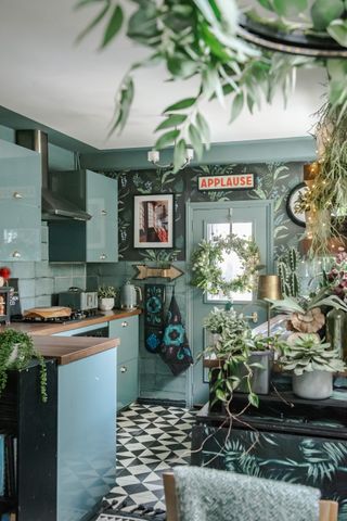 Dark jungle wallpapered kitchen with greenery and sage green cabinetry