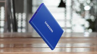 A blue Samsung T7 hard drive standing upright on a wooden table