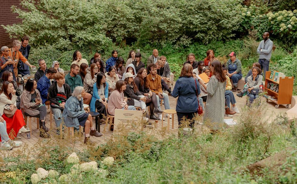 A group of people planting, mingling, and reading in a community garden.