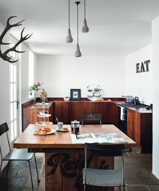 An example of small kitchen layout ideas showing a U-shaped kitchen and dining area in dark wood with white walls