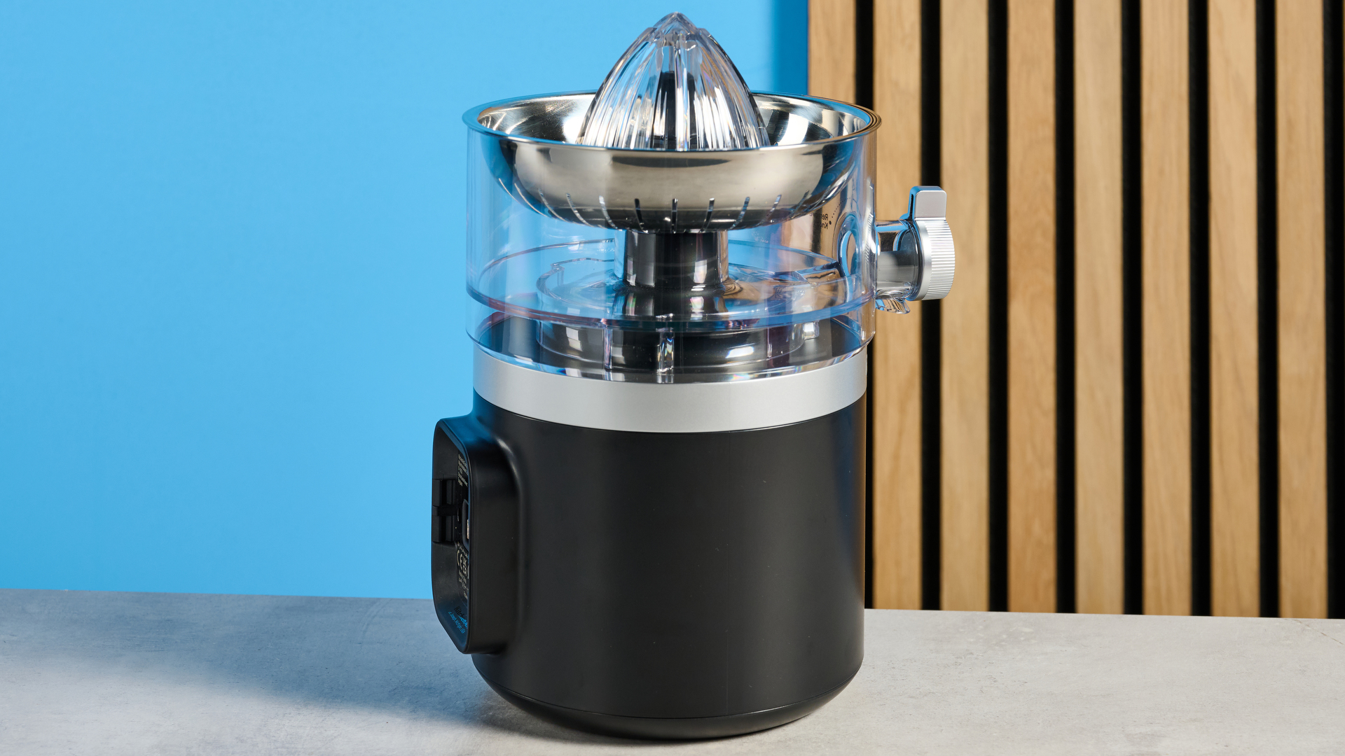 KitchenAid Go Cordless Citrus Juicer in matte black photographed in front of a blue background.