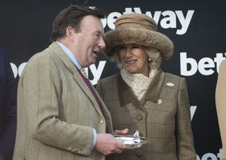 Queen Camilla wearing a tan fur hat talking to Nicky Henderson at Cheltenham Ladies Day 2018