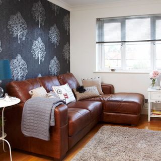 living room with grey wallpaper on wall and lather brown sofa