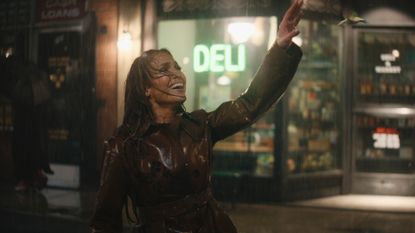 a woman (jennifer lopez) raises her hand while singing in the rain