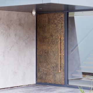 brown textured door with front door wall and camera