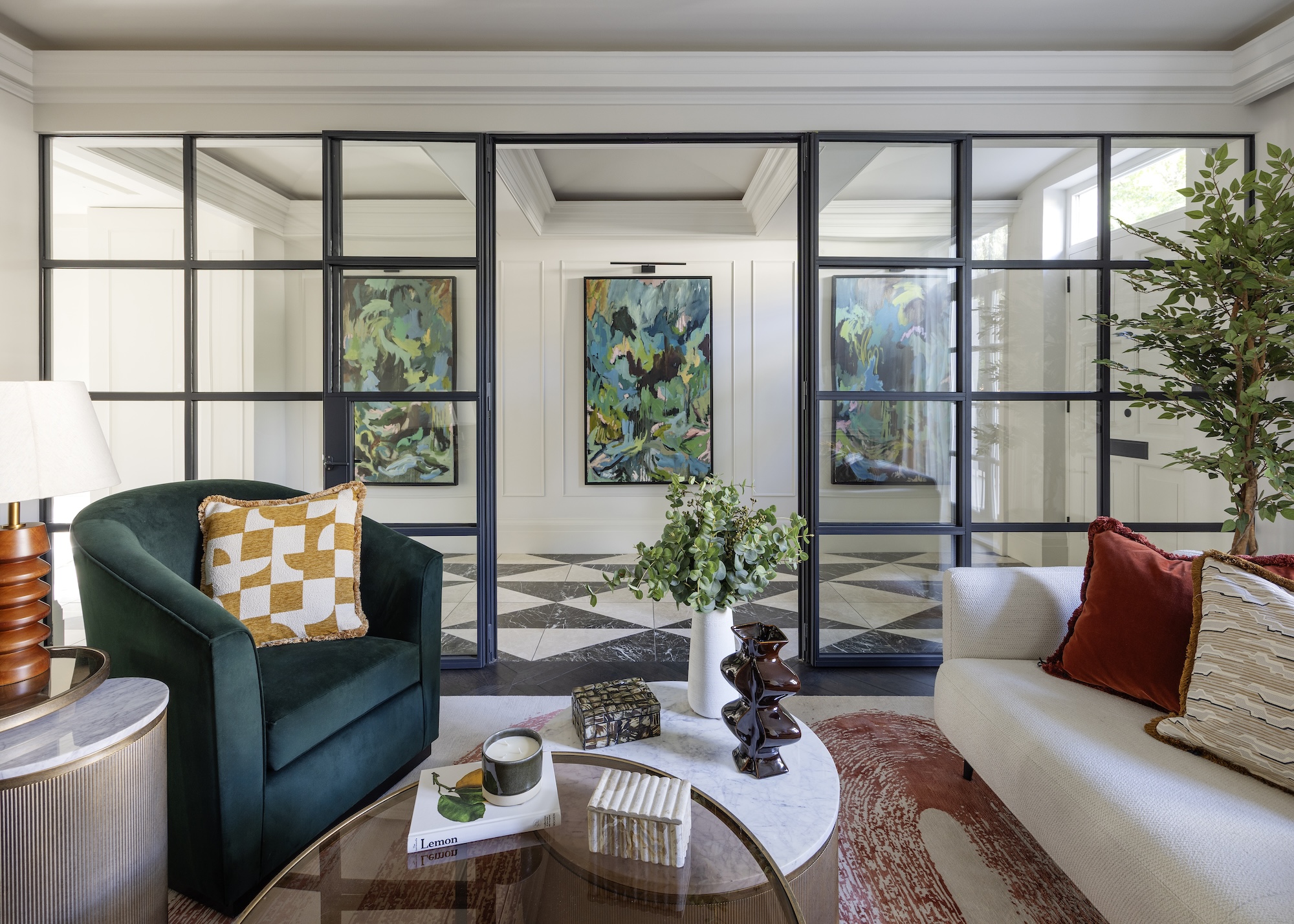 A sitting room with sofas and a coffee table linked to the hallway with Crittall style glazing