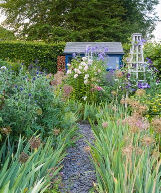 slate path through a cutting garden with obelisk and shed