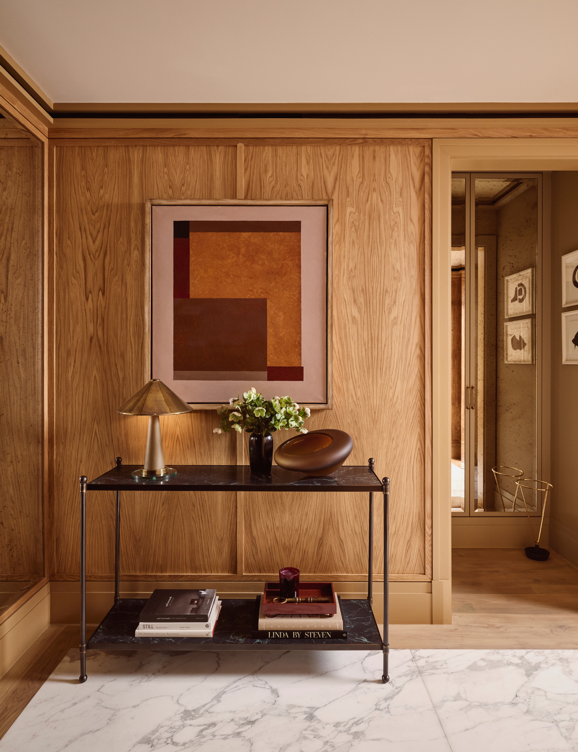 Wood paneled entryway area featuring a two-tier black metal table holding various collected objects
