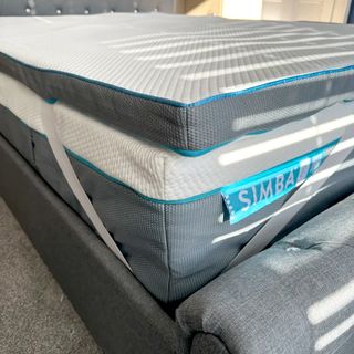 The corner of the Simba Hybrid mattress topper showing its elsaticated straps holding it in place on top of a Simba mattress