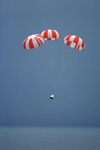 A SpaceX Dragon crew capsule prototype parachutes down to an ocean landing after a launch abort system test from Cape Canaveral Air Force Station, Florida on May 6, 2015. Riding aboard was a human-shaped dummy.