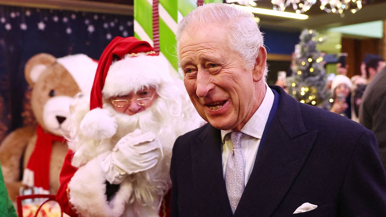 King Charles III smiling while meeting Santa Claus at a shopping center in west London.