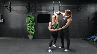 NASM-certified personal trainer Brandon Polk coaches a female client through the movement of an overhead band distraction