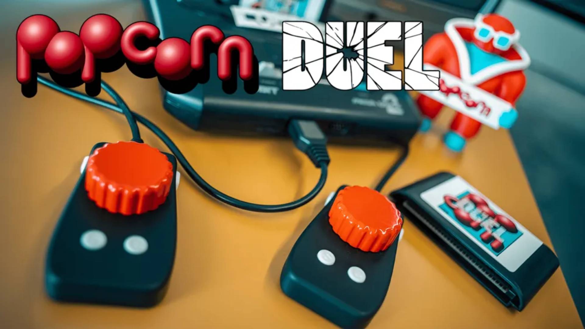 Two Popcorn Duel paddle controllers in front of Sega Mega Drive 2 and Mr Popcorn figure.