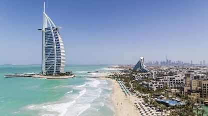 External drone shot of Jumeirah Burj Al Arab hotel with Dubai downtown in background