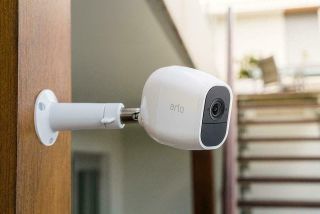 White Arlo security camera mounted on indoor beam