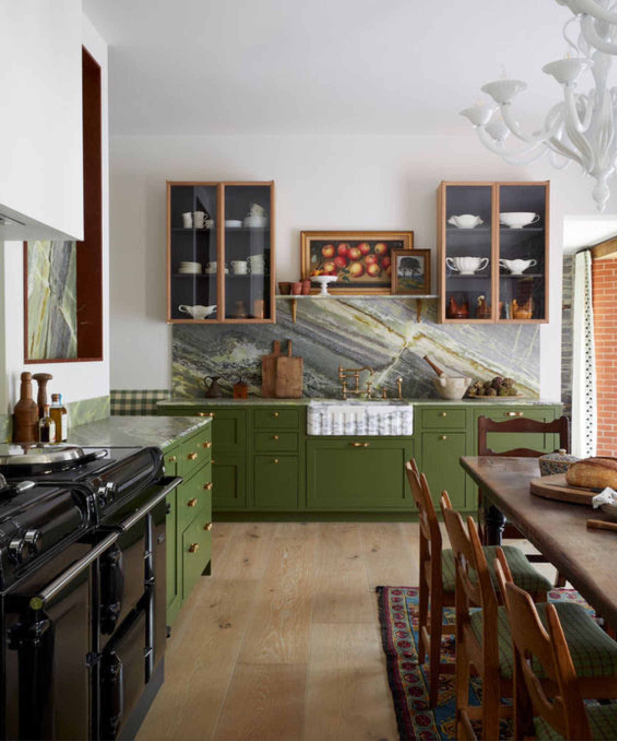 A kitchen with green cabinets, white walls, a wooden dining table, and wooden glass-fronted cabinets on the walls