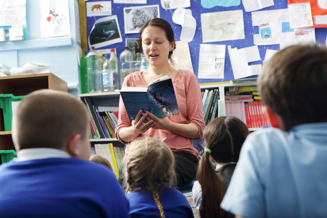 A teacher is reading a book to her students 