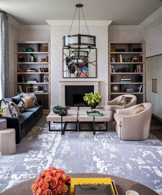 Pale taupe apartment living room decorated with art and bookcases either side of a fireplace