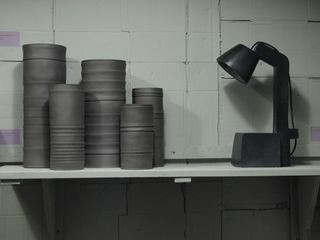 Black porcelain vessels on a table with a black lamp
