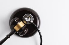 A stethoscope positioned on a gavel, symbolizing law and healthcare.