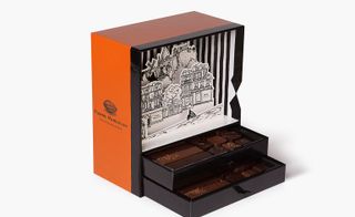 An open chocolate box displaying the chocolates inside, and with the pop-up scene and orange colour option