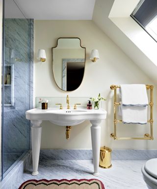 neutral bathroom with curved traditional style washstand, gold towel radiator and marble