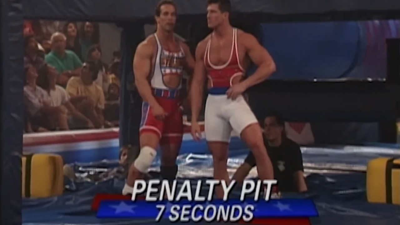 Two male gladiators standing in the Penalty Pit in spandex in American Gladiators S4 E4.