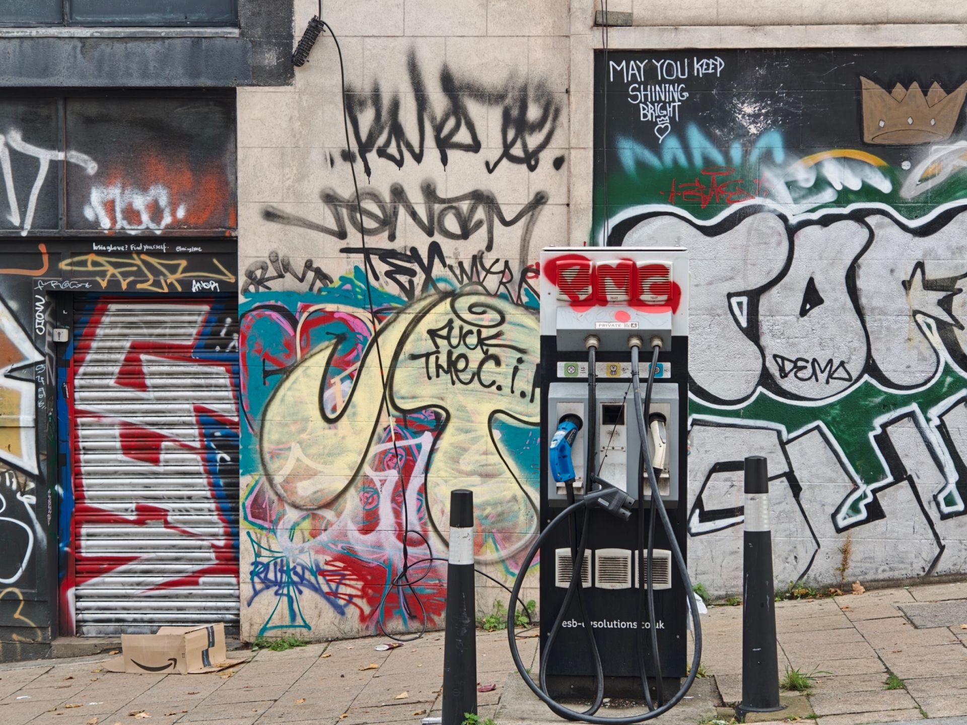 An EV charger with graffiti in the background