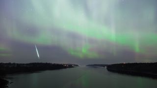 A meteor falls to Earth with a green aurora in the background