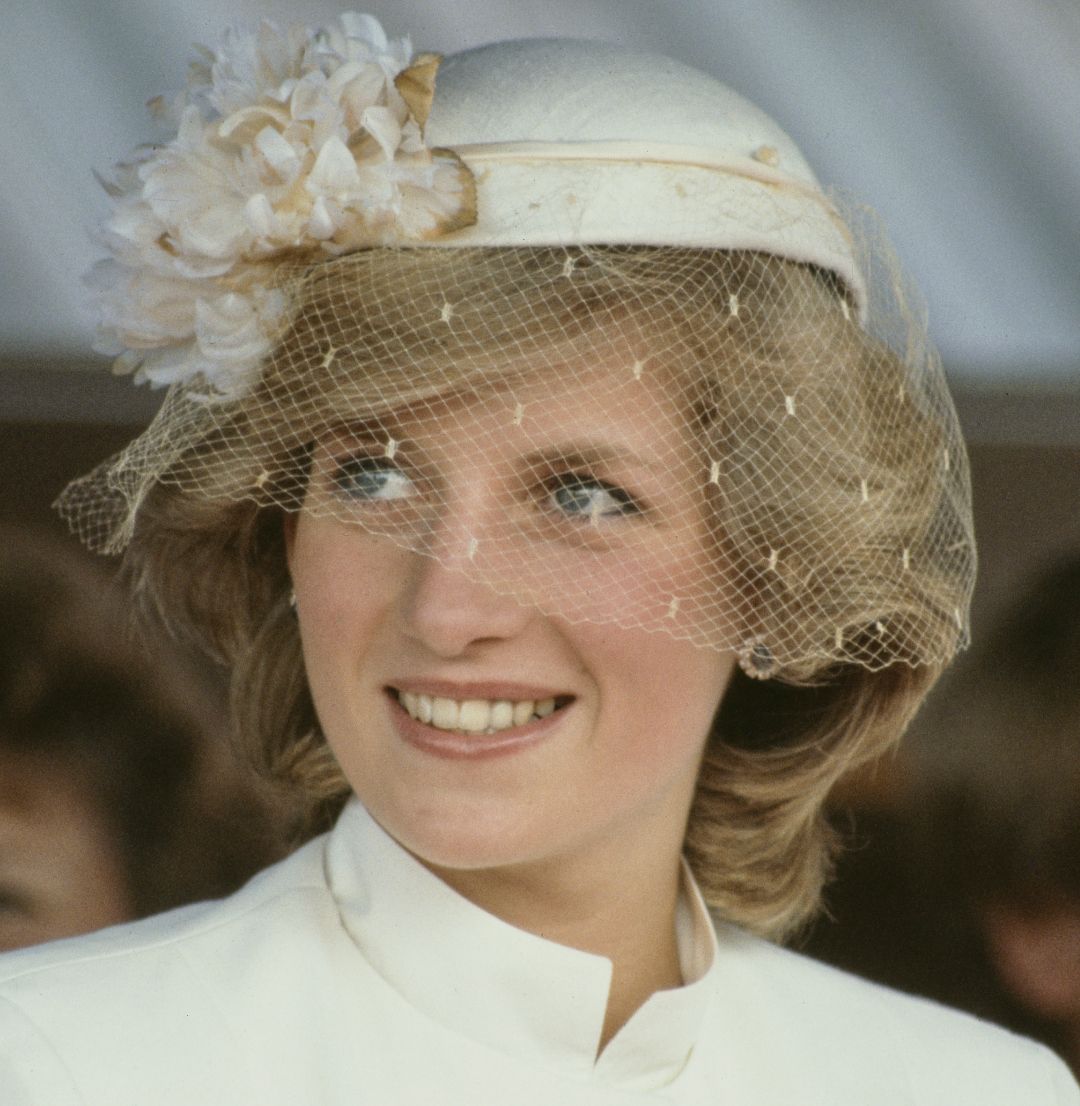 Princess Diana wearing a white veiled hat and smiling