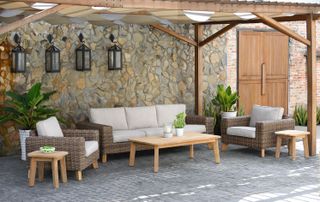 outdoor porch with rattan sofa and chairs, coffee table stone wall