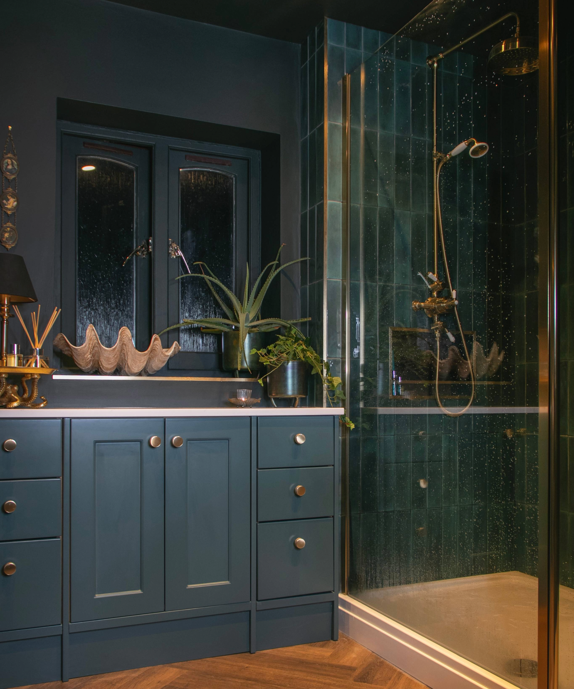 Dark bathroom idea with dark green vanity unit and tiles and gold accents